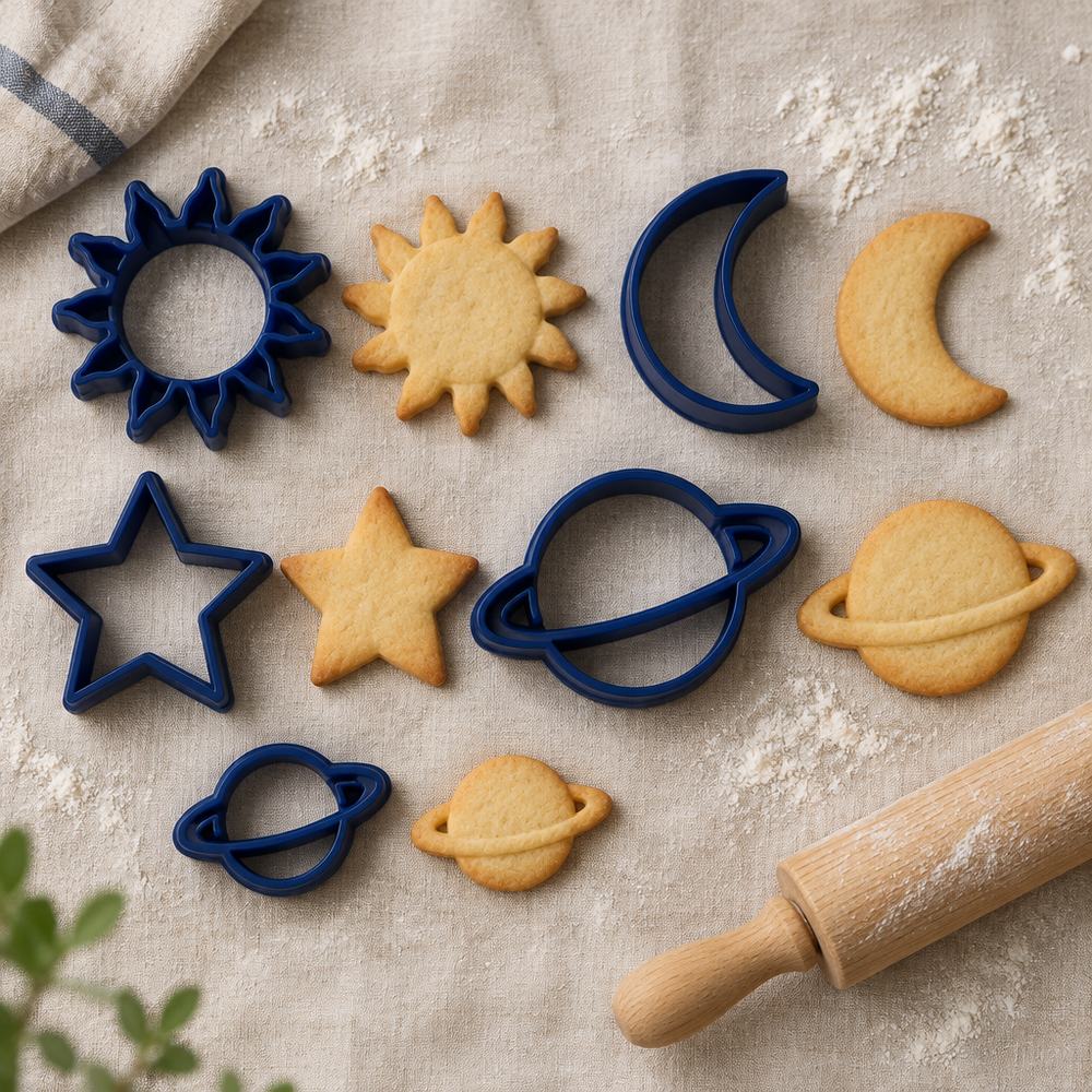 Pack de cinco cortadores de galletas de espacio junto a sus galletas horneadas