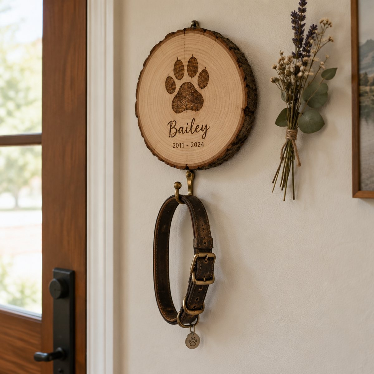 Placa homenaje de mascota colgada en la pared de la entrada con el collar colgado de su gancho